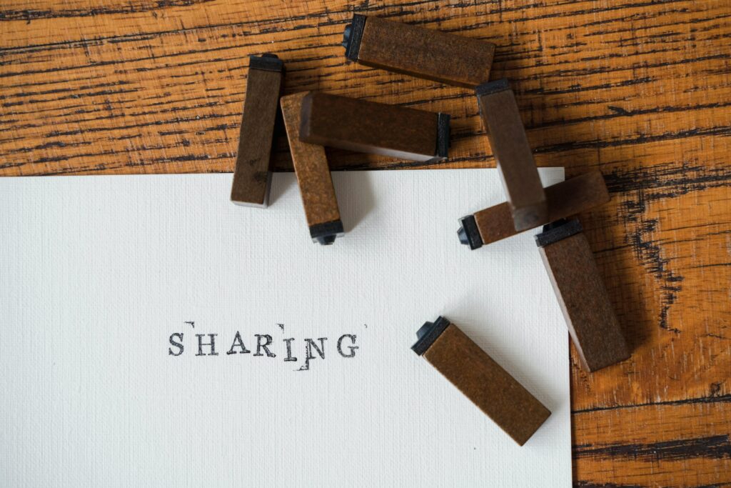 Close-up of ink stamps spelling 'SHARING' on a wooden surface.