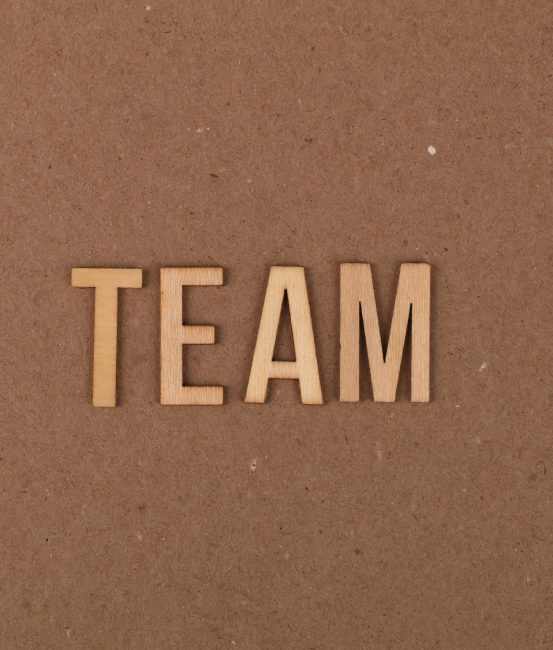 Wooden letters on a brown background spelling 'TEAM' symbolize teamwork and collaboration.