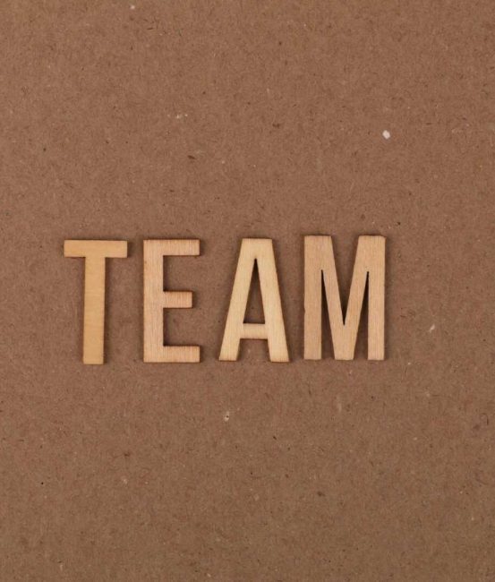 Wooden letters on a brown background spelling 'TEAM' symbolize teamwork and collaboration.