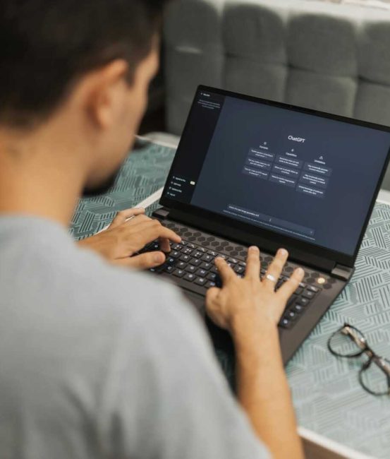 A man working on a laptop displaying ChatGPT's interface in an indoor setting.