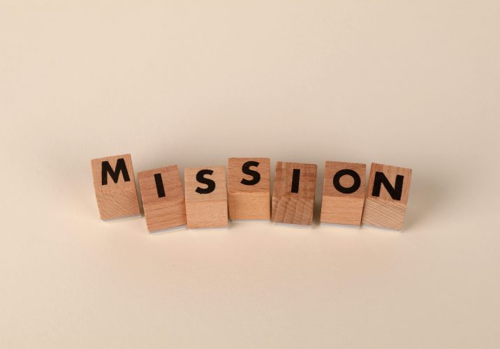 Wooden blocks with letters spelling 'MISSION' against a neutral beige backdrop.