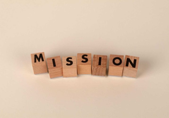 Wooden blocks with letters spelling 'MISSION' against a neutral beige backdrop.