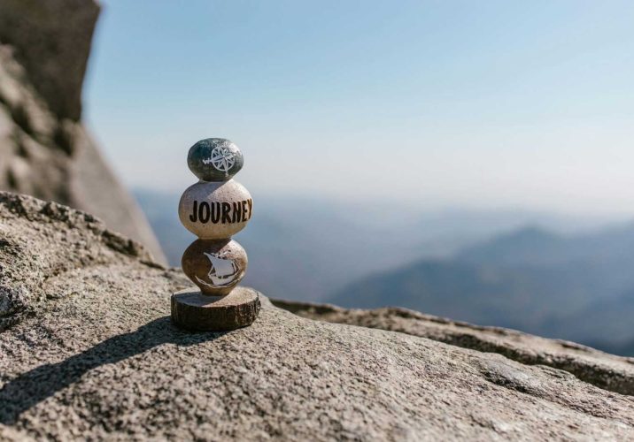 A serene image of stacked stones with 'Journey' text on a mountain peak.